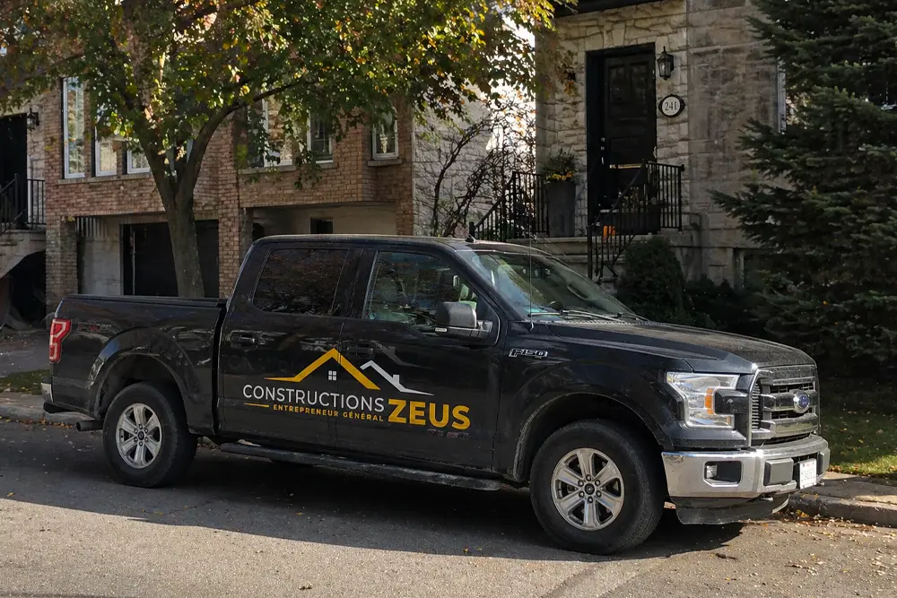 black pickup truck with constructions Zeus logo on the side parked outside residential home in Montreal